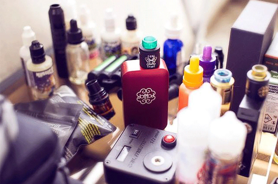 Vaporesso vape mod and various vaping accessories, including e-liquids and other equipment, on a table.
